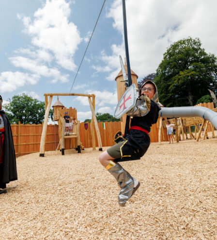Family enjoying a medieval-themed park with costume play on sunny day.