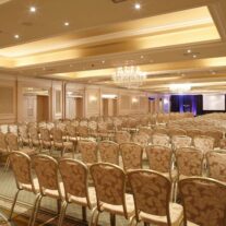 Elegant conference room with chandeliers and rows of chairs, ready for a hospitality event.