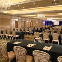 Elegant hotel conference room set for a business event with chandeliers and arranged seating.