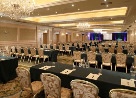 Elegant hotel conference room set for a business event with chandeliers and arranged seating.
