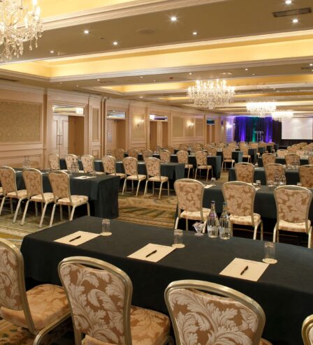 Elegant hotel conference room set for a business event with chandeliers and arranged seating.