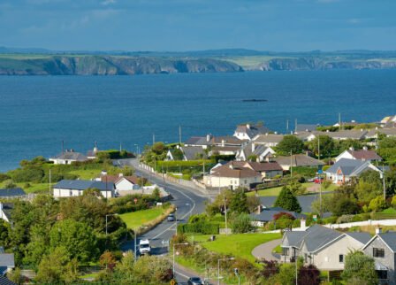 Coastal village with charming cottages and sea views under a clear blue sky.