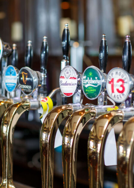 A variety of beer taps at a cosy pub, offering different brews for guests to enjoy.