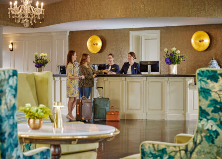 A welcoming hotel reception with a couple checking in, assisted by friendly staff.