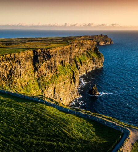 Family enjoying sunset at scenic coastal cliffs.