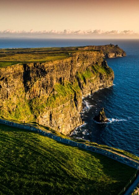 Family enjoying sunset at scenic coastal cliffs.