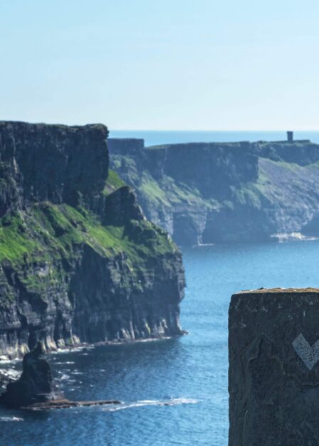 Scenic view of dramatic cliffs by the sea under a clear sky, inviting exploration.