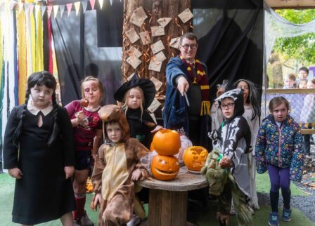 A family dressed in Halloween costumes enjoys a festive gathering with carved pumpkins.