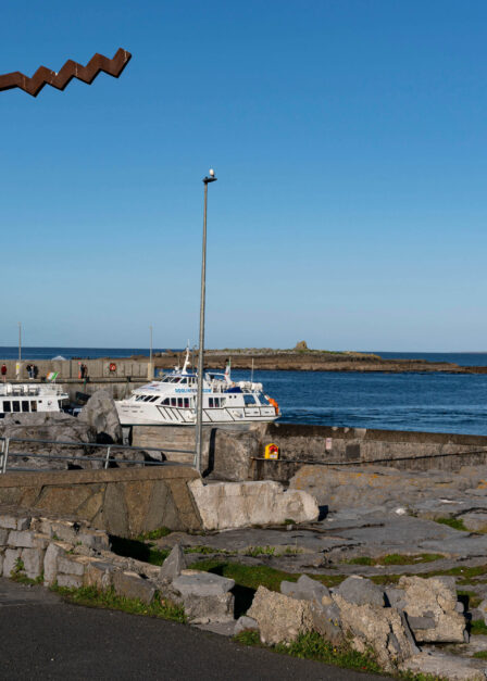 Scenic coastal harbour with boats and clear blue sky.