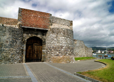 Historic stone fortress with wooden gate under a partly cloudy sky