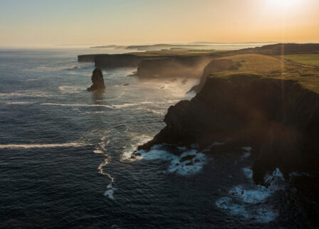 Coastal cliffs at sunset with families enjoying scenic views.