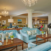 Elegant hotel lounge with a family relaxing on plush sofas, adorned with chandeliers and floral decor.