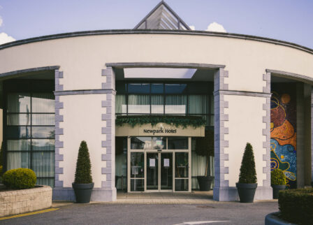 Family arriving at welcoming hotel entrance, lush greenery and vibrant artwork