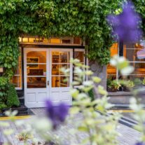 Inviting hotel entrance with lush greenery and warm lighting.