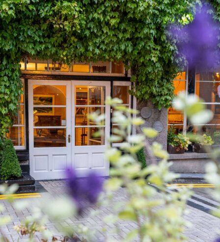 Inviting hotel entrance with lush greenery and warm lighting.
