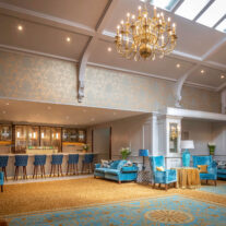 Elegant hotel lounge with plush seating and a well-stocked bar under grand chandeliers.