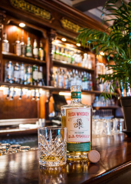 Warm hotel bar with whiskey bottle and glass, inviting atmosphere.