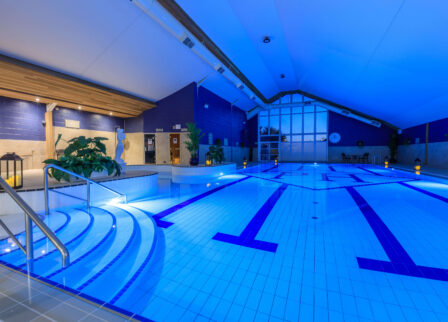 Indoor hotel pool with soft lighting and steps, inviting for family relaxation.