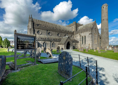 Family exploring St Canice’s Cathedral grounds under a sunny sky.