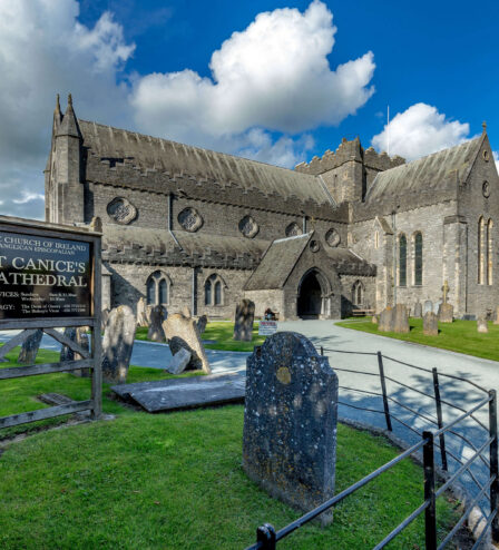 Family exploring St Canice’s Cathedral grounds under a sunny sky.