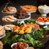 A lavish dessert table with assorted pastries, cakes, and fruit tarts in a warm, inviting setting.