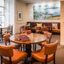 Cosy hotel lounge with round tables and inviting decor.