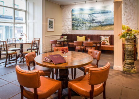 Cosy hotel lounge with round tables and inviting decor.