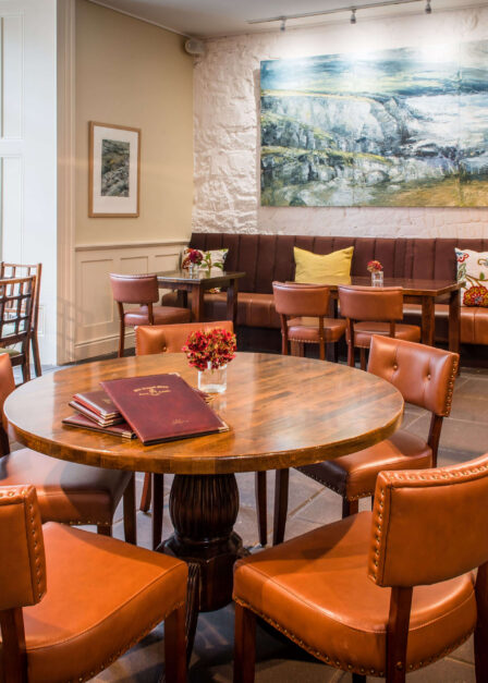 Cosy hotel lounge with round tables and inviting decor.
