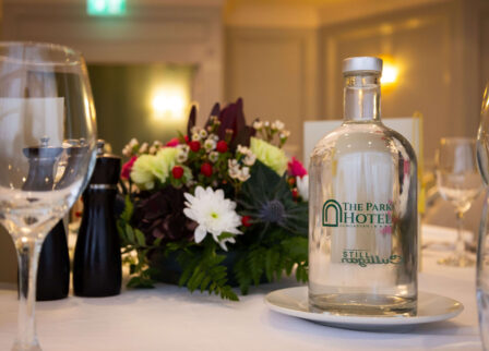 Elegant hotel dining setup with water bottle and flowers.