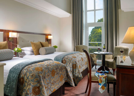 Cosy hotel room with twin beds, elegant decor, and a scenic view for a relaxing stay.