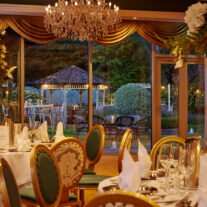 Elegant dining room with ornate decor and garden view at a luxurious hotel.